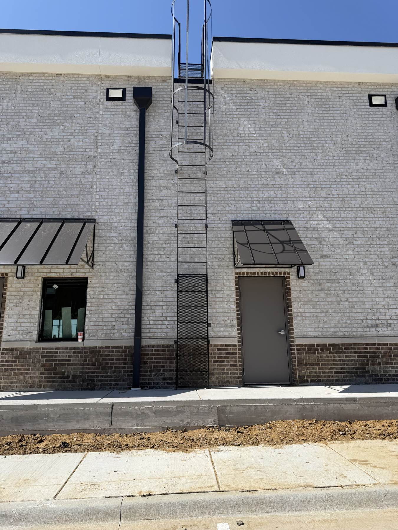 Exterior steel roof-access ladder installed on a commercial building