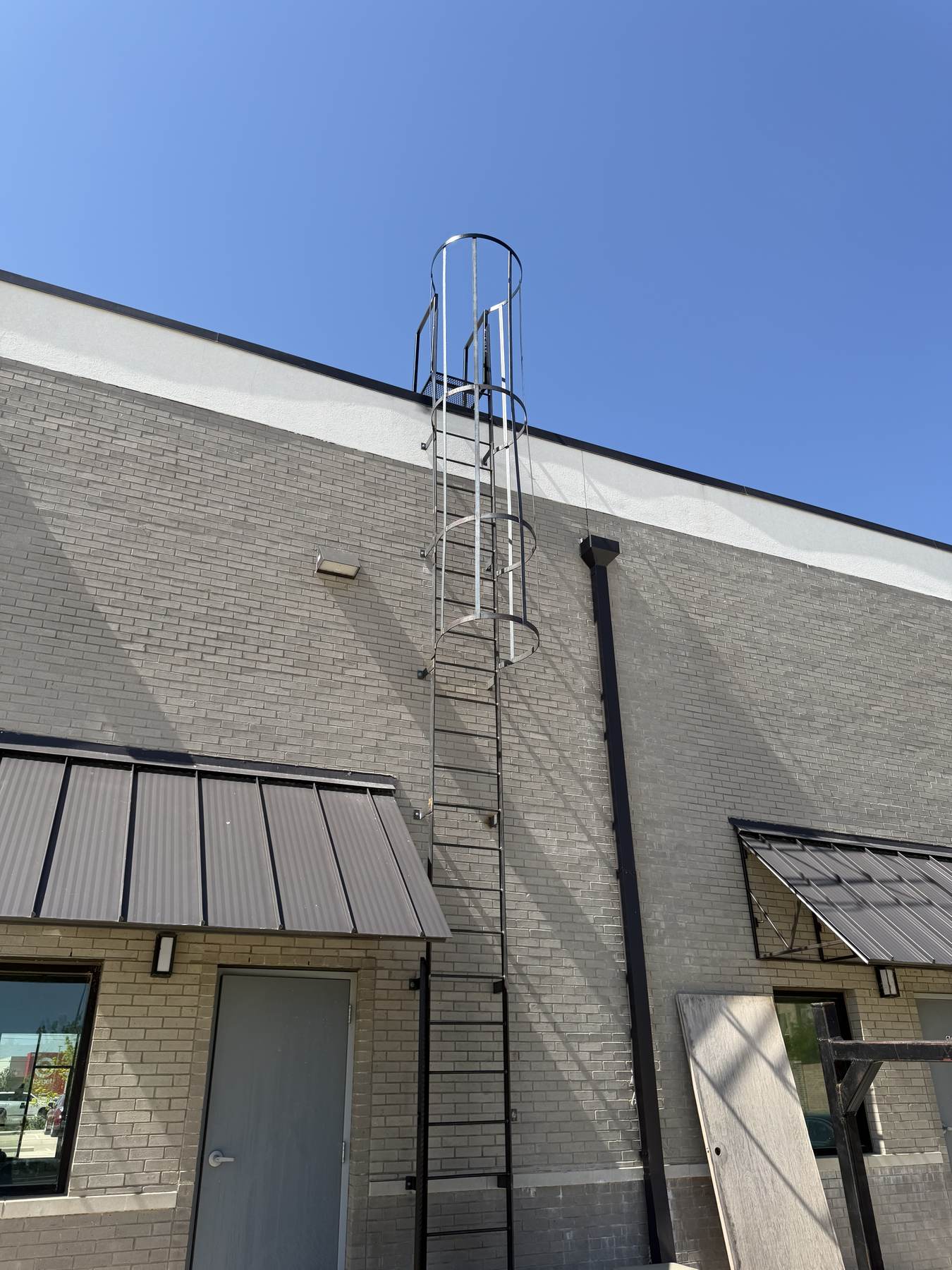 Steel rooftop access ladder mounted to a commercial building exterior